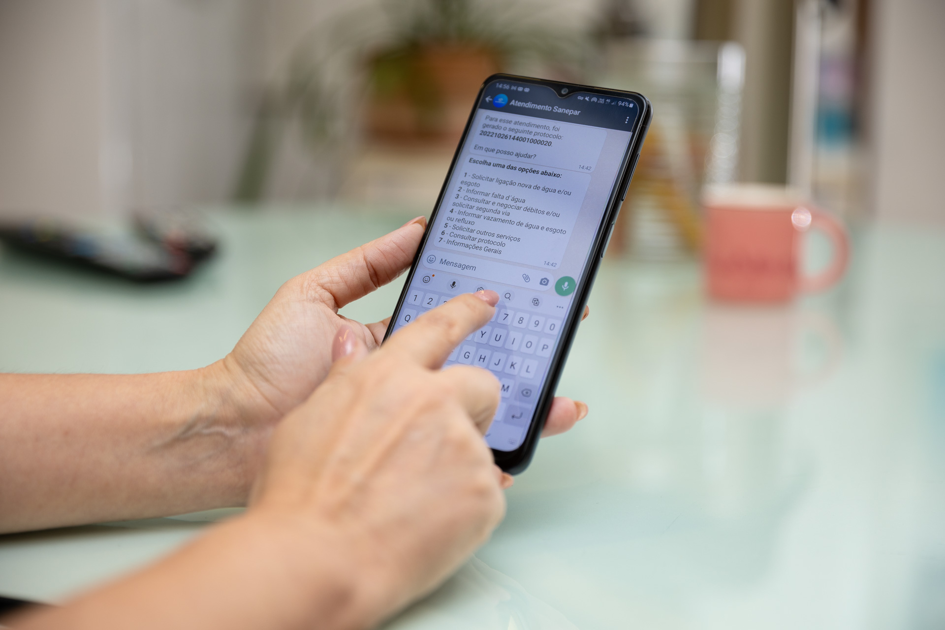 Mãos segurando celular com whatsapp da Sanepar