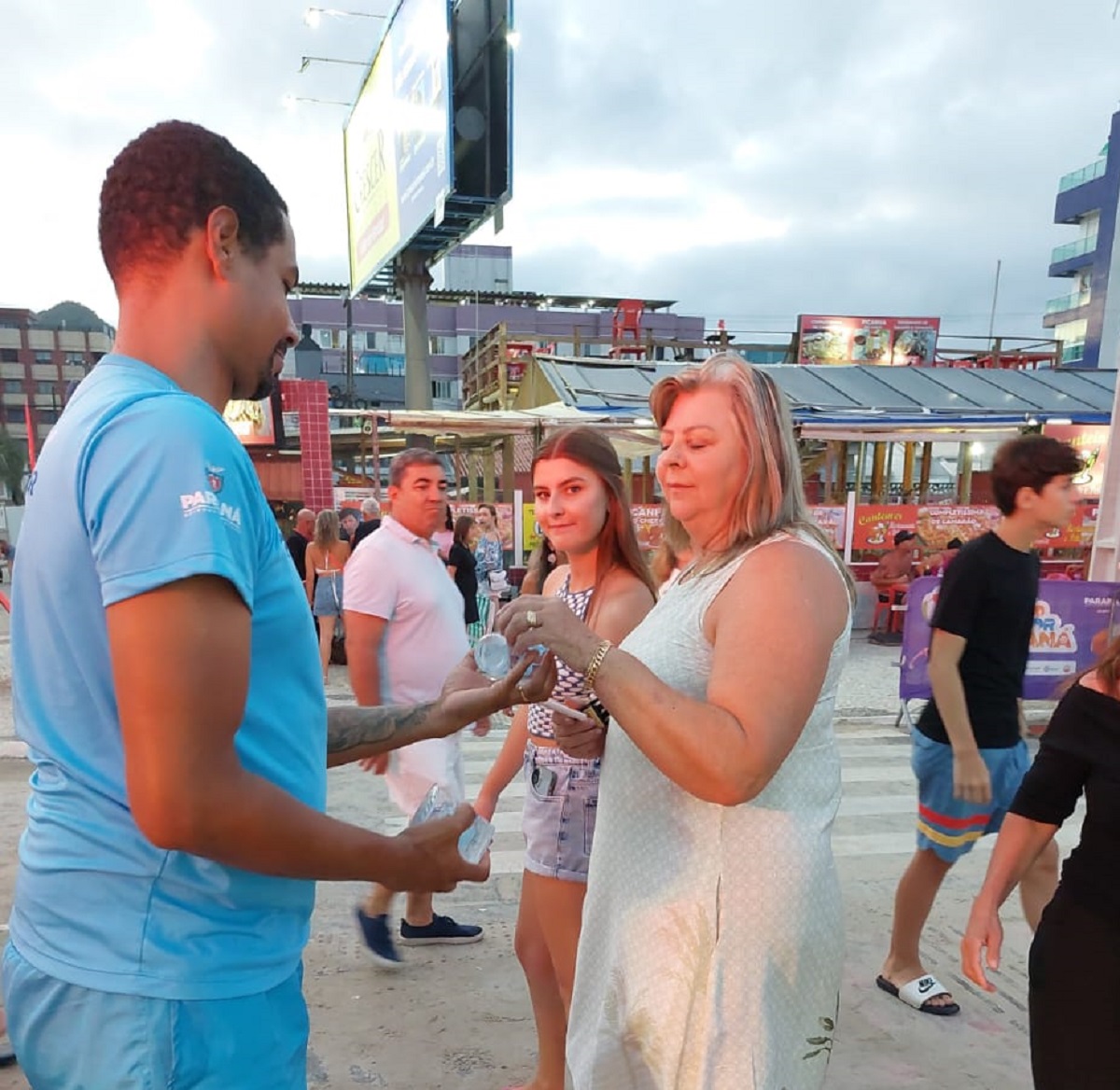 Agente da Sanepar distribui copos de água nas praias