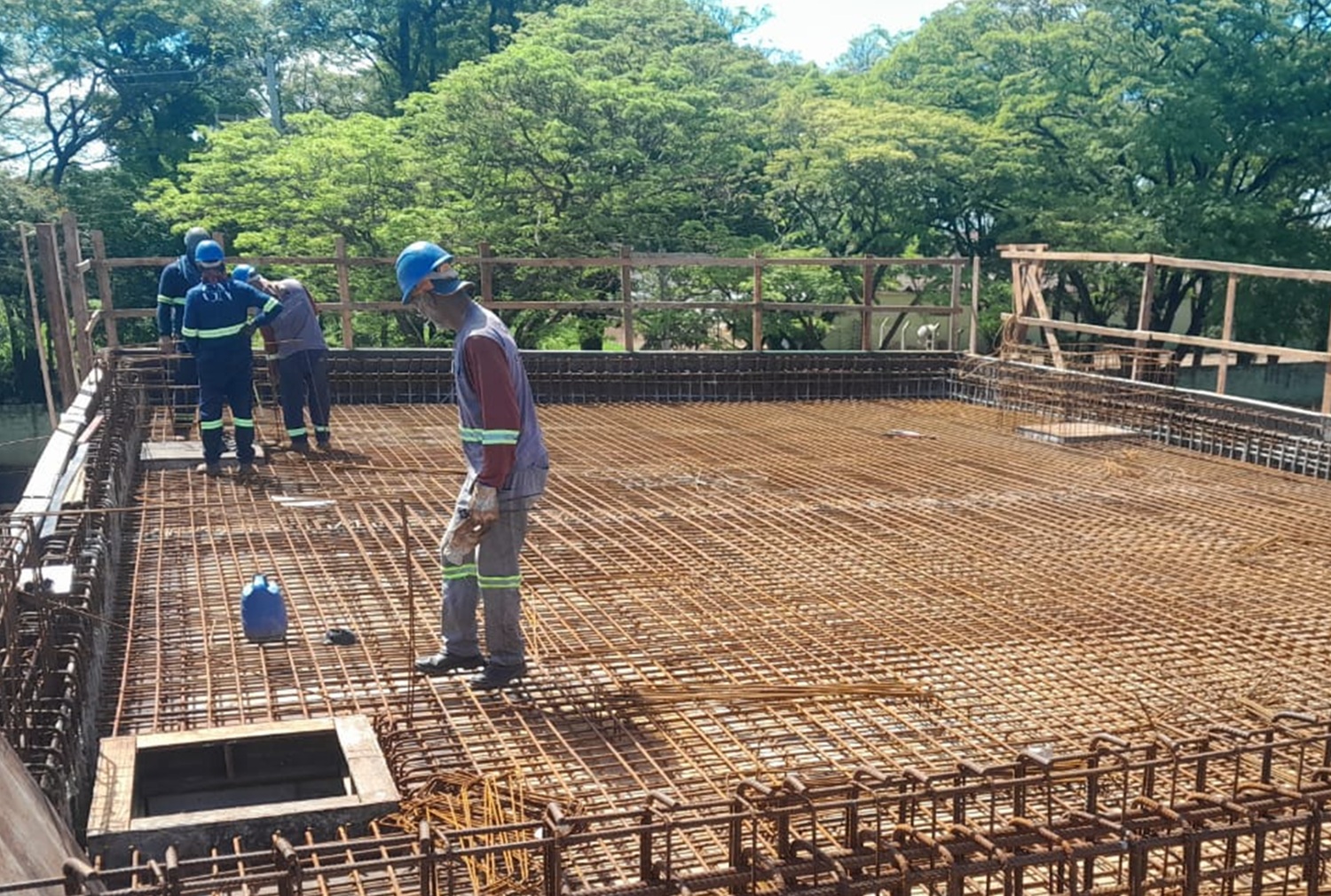 trabalhadores sobre a laje do reservatório em construção, com ferragem aparente