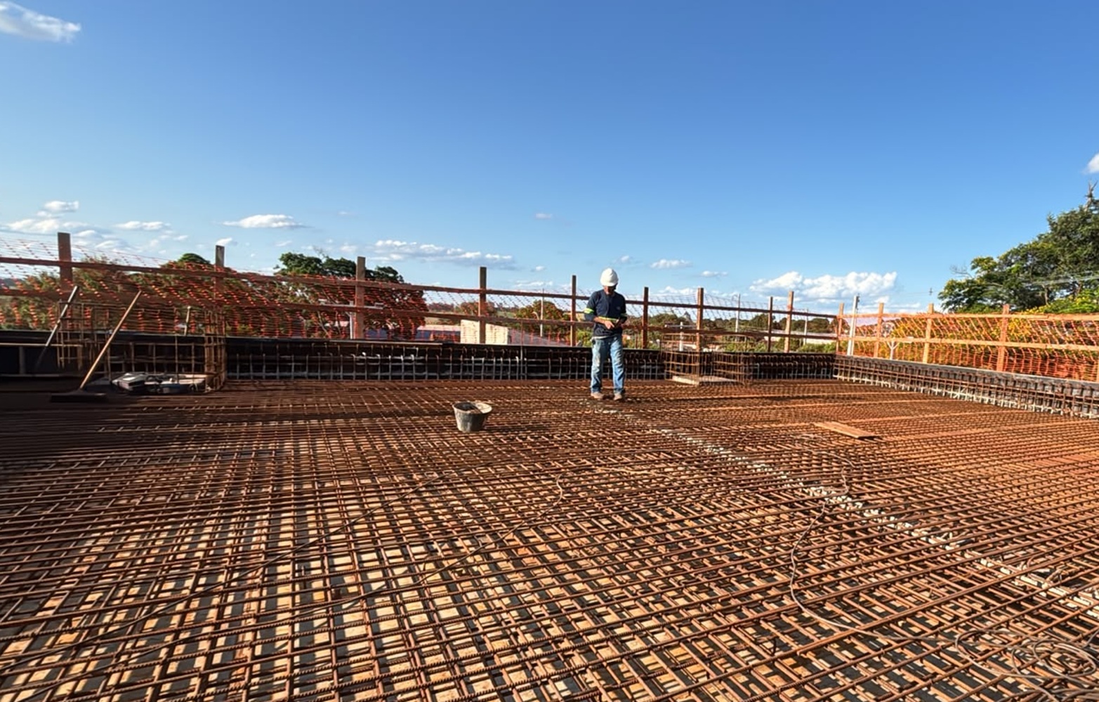 trabalhador sobre a laje do reservatório em construção, com ferragem aparente