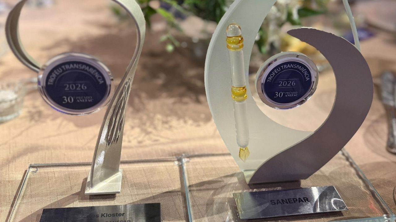 Dois troféus de acrílico e vidro exibem o selo "Troféu Transparência 2026 - 30º Prêmio ANEFAC", com uma placa contendo o nome Sanepar na base do troféu à direita.
