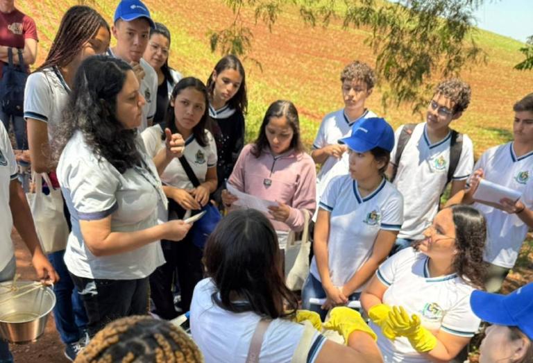 alunos estão num espaço aberto proximo ao rio e estão analisando a qualidade da agua com kit 