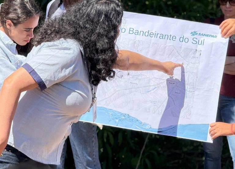 alunos estão num espaço aberto proximo ao rio discutindo em circulo sobre a bacia hidrográfica
