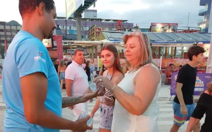 Agente da Sanepar distribui copos de água nas praias