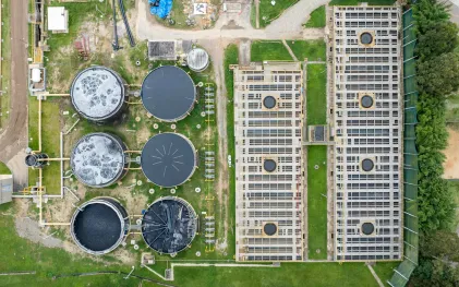 Vista aérea da Estação de Tratamento de Esgoto, mostrando seis tanques circulares e grandes reservatórios retangulares ladeados por área verde.