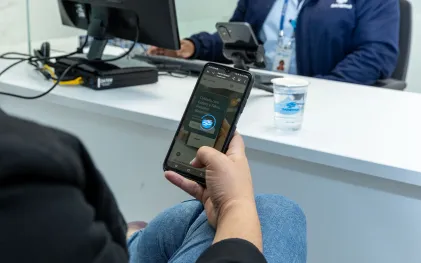 clientes está no atendimento da sanepar e está usando o celular. cliente tem cabelos cacheados e aparece de costas