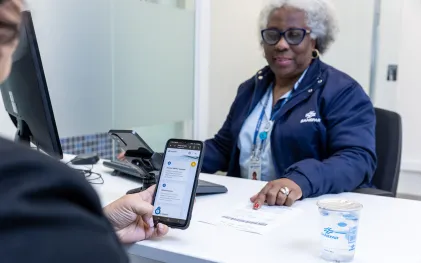 clientes está no atendimento da sanepar e está usando o celular. uma mulher negra e de cabelos brancos é a atendente