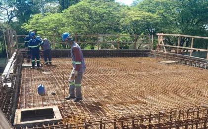 trabalhadores sobre a laje do reservatório em construção, com ferragem aparente