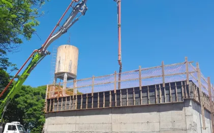 caminhão com uma bomba está enchendo a laje do reservatório em construção de concreto