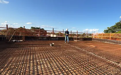 trabalhador sobre a laje do reservatório em construção, com ferragem aparente