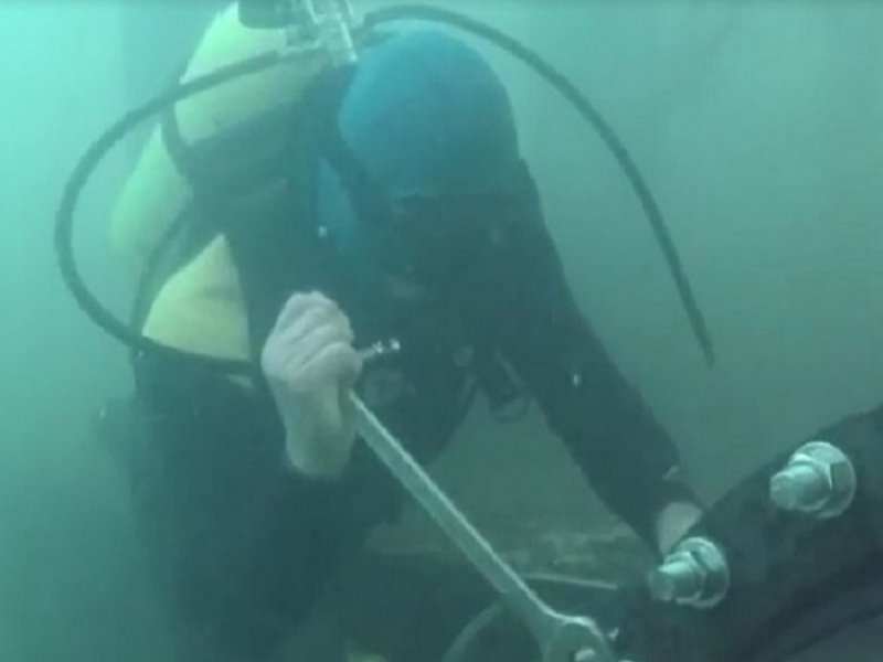 Mergulhador usando ferramenta para apertar parafuso embaixo da água