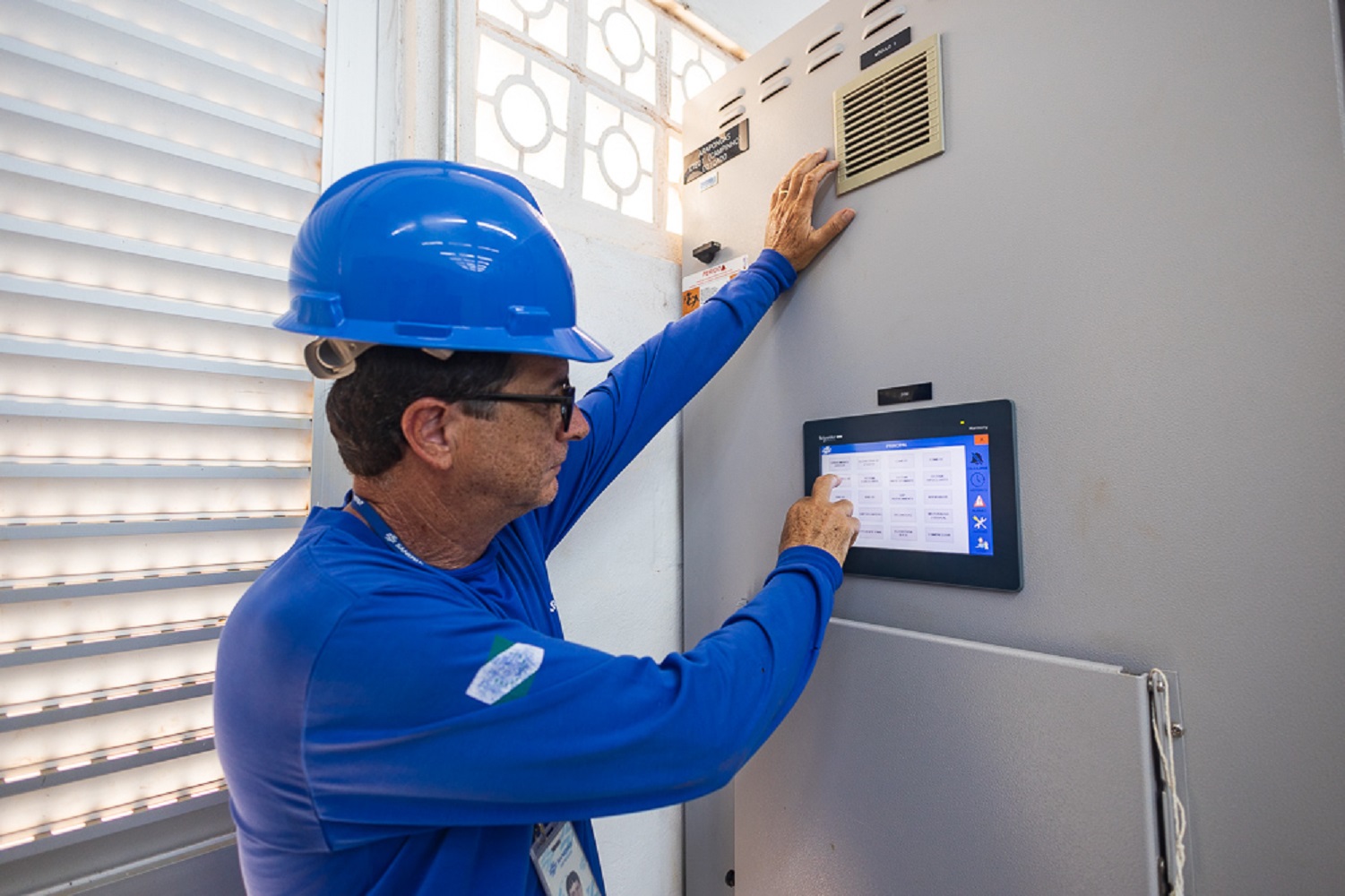 trabalhador acessa painel de comando de automação em estação de tratamento de esgoto