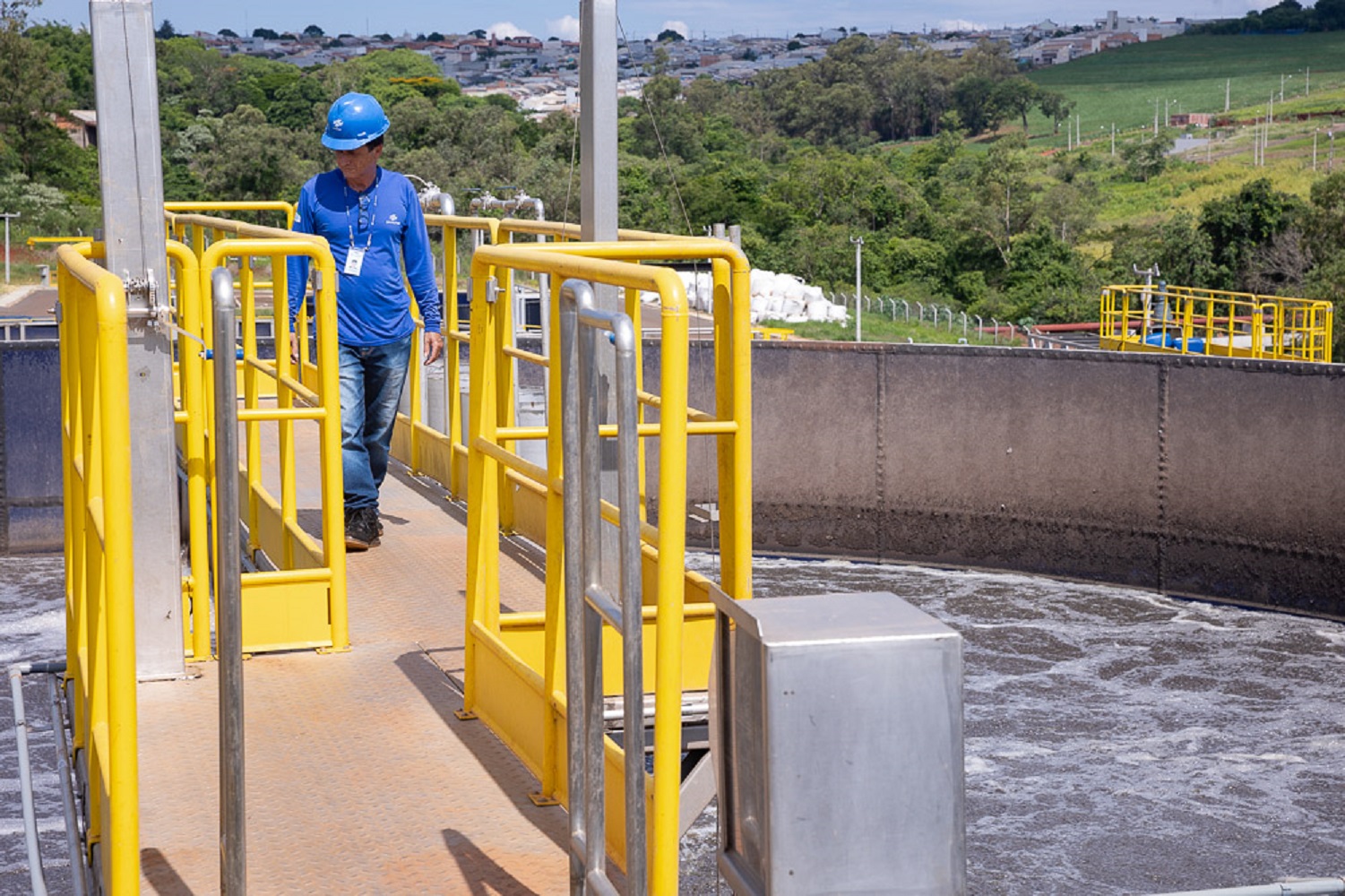 trabalhador caminho em passarela numa estação de tratamento de esgoto