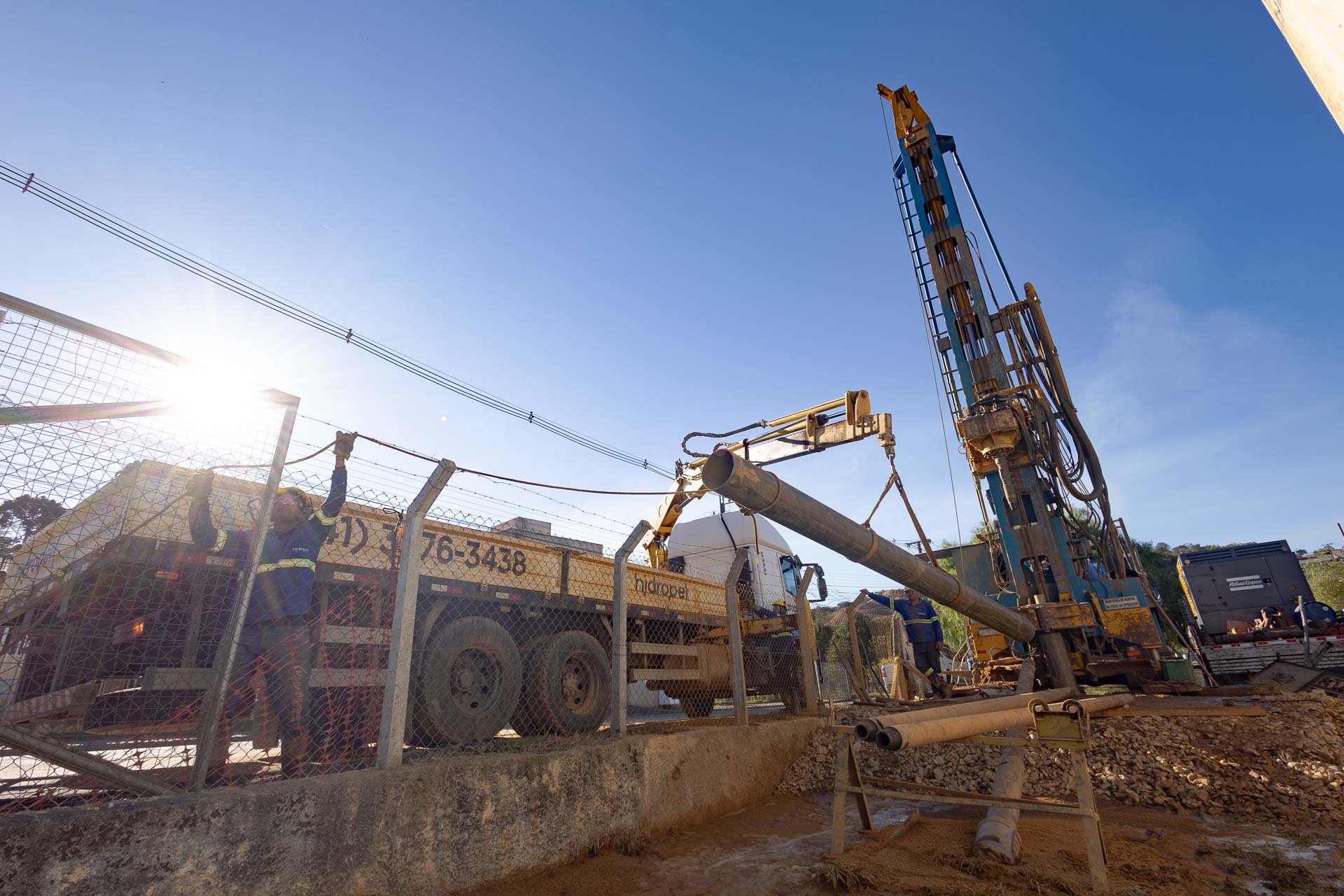 Equipes e máquinas trabalhando em perfuração de poço