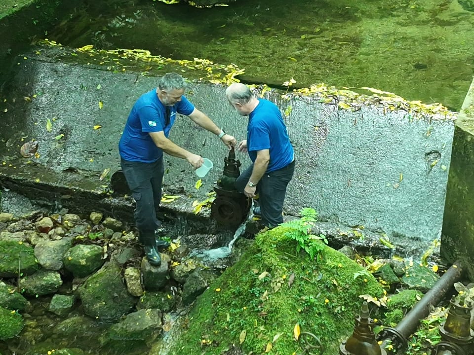 homens coletando amostra de água do rio