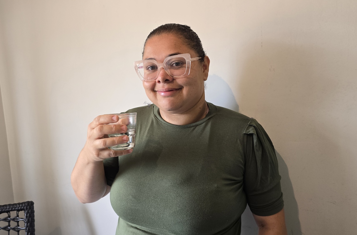 mulher sorri com copo de água na mão