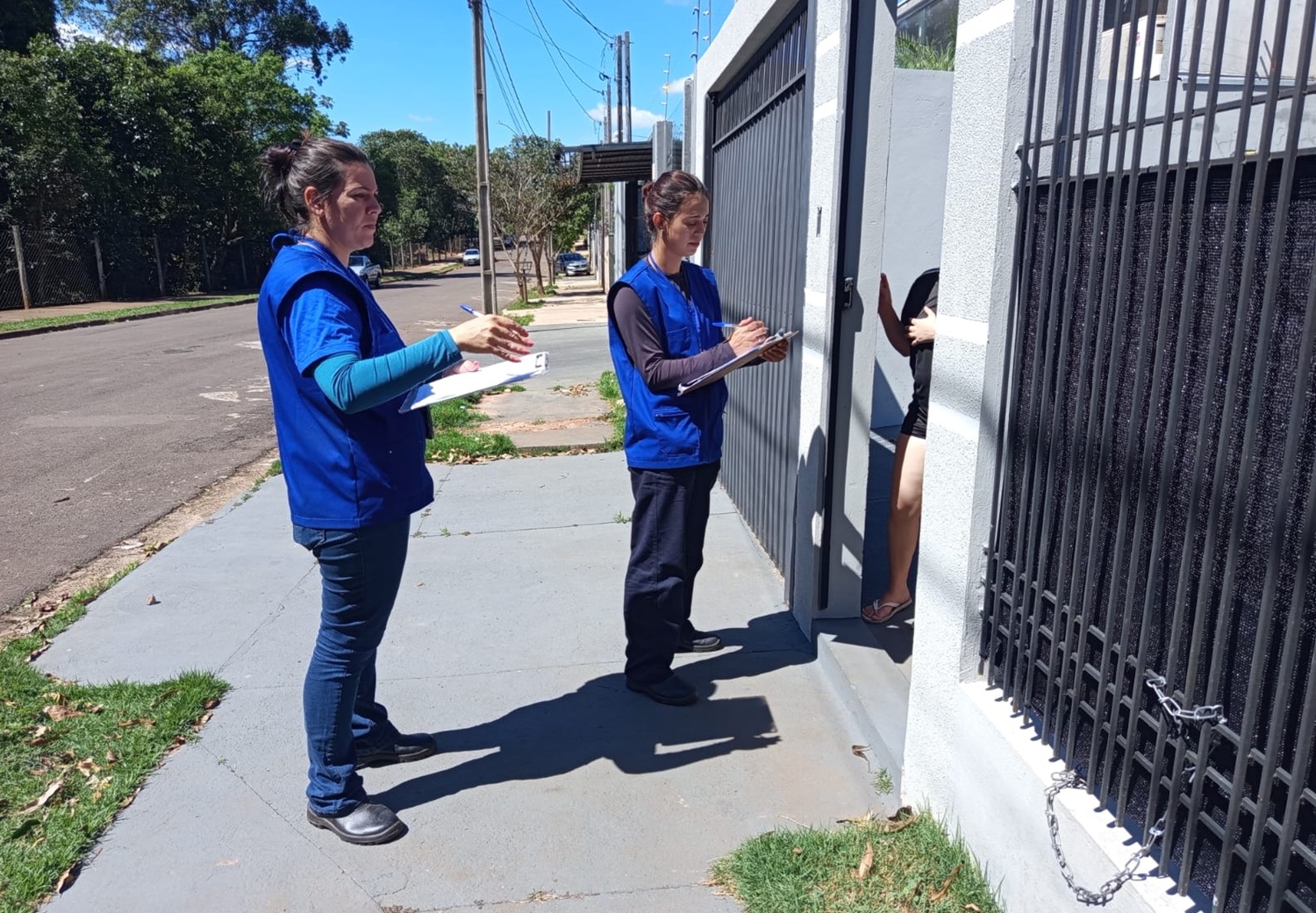 técnicos com uniformes da cor azul abordam clientes no portão de suas casas