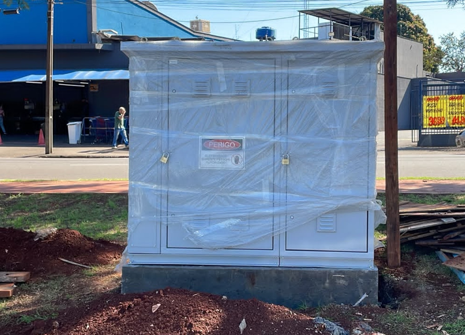 quadro de comando elétrico, parece uma armário de metal com duas portas, na cor cinza. fica num canteiro de uma rua