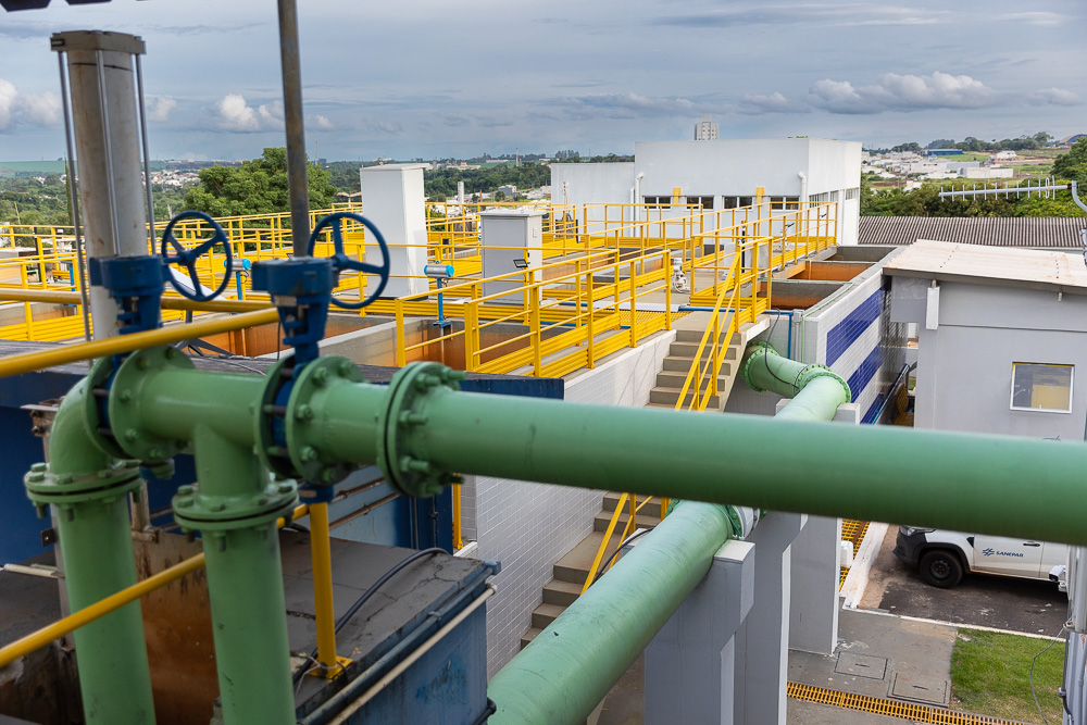 Vista superior de tanques abertos de concreto de uma estação de tratamento de água, mostrando as etapas de movimentação e purificação da água sob a luz do dia.