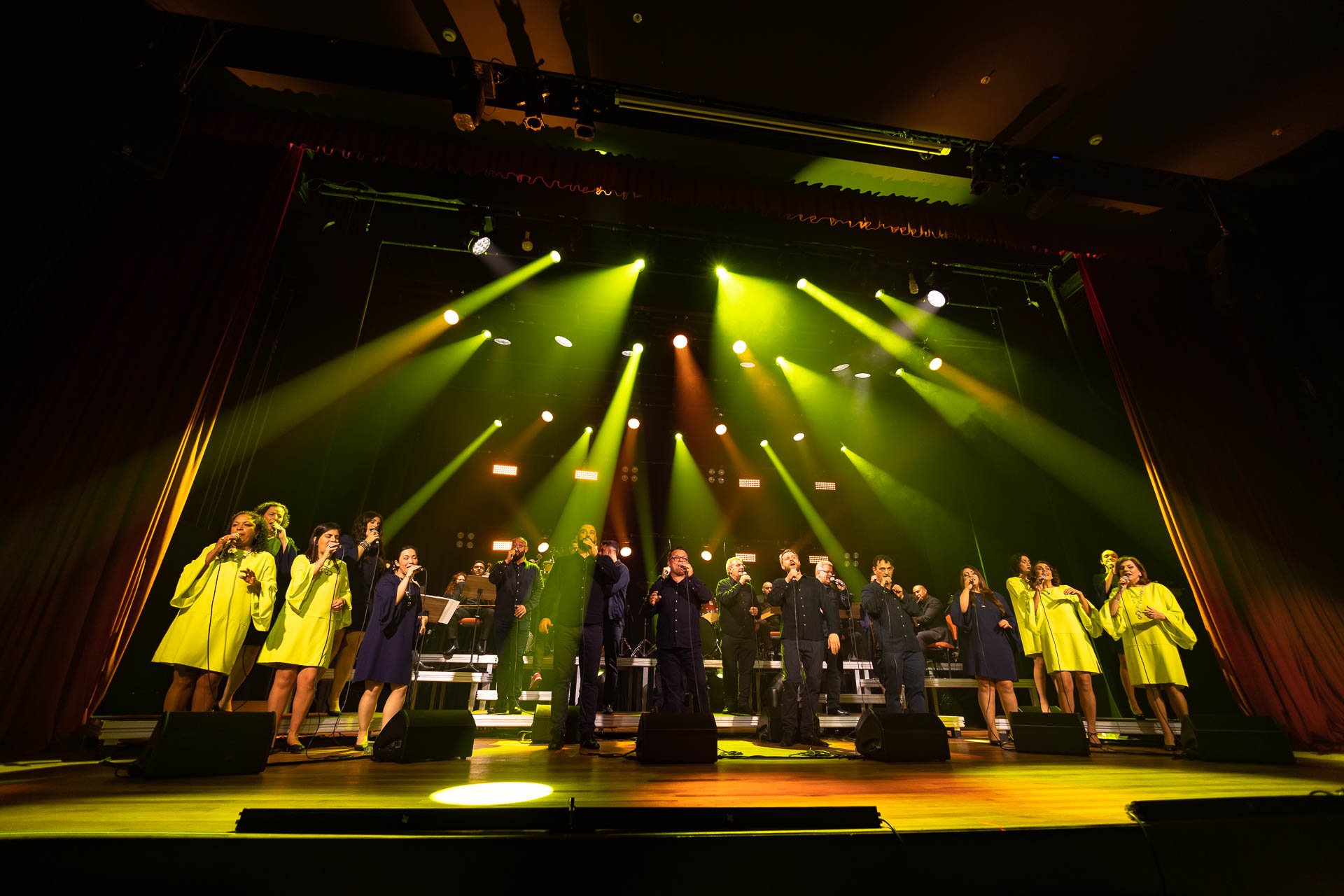 grupo vocal em apresentação musical num palco bastante iluminado