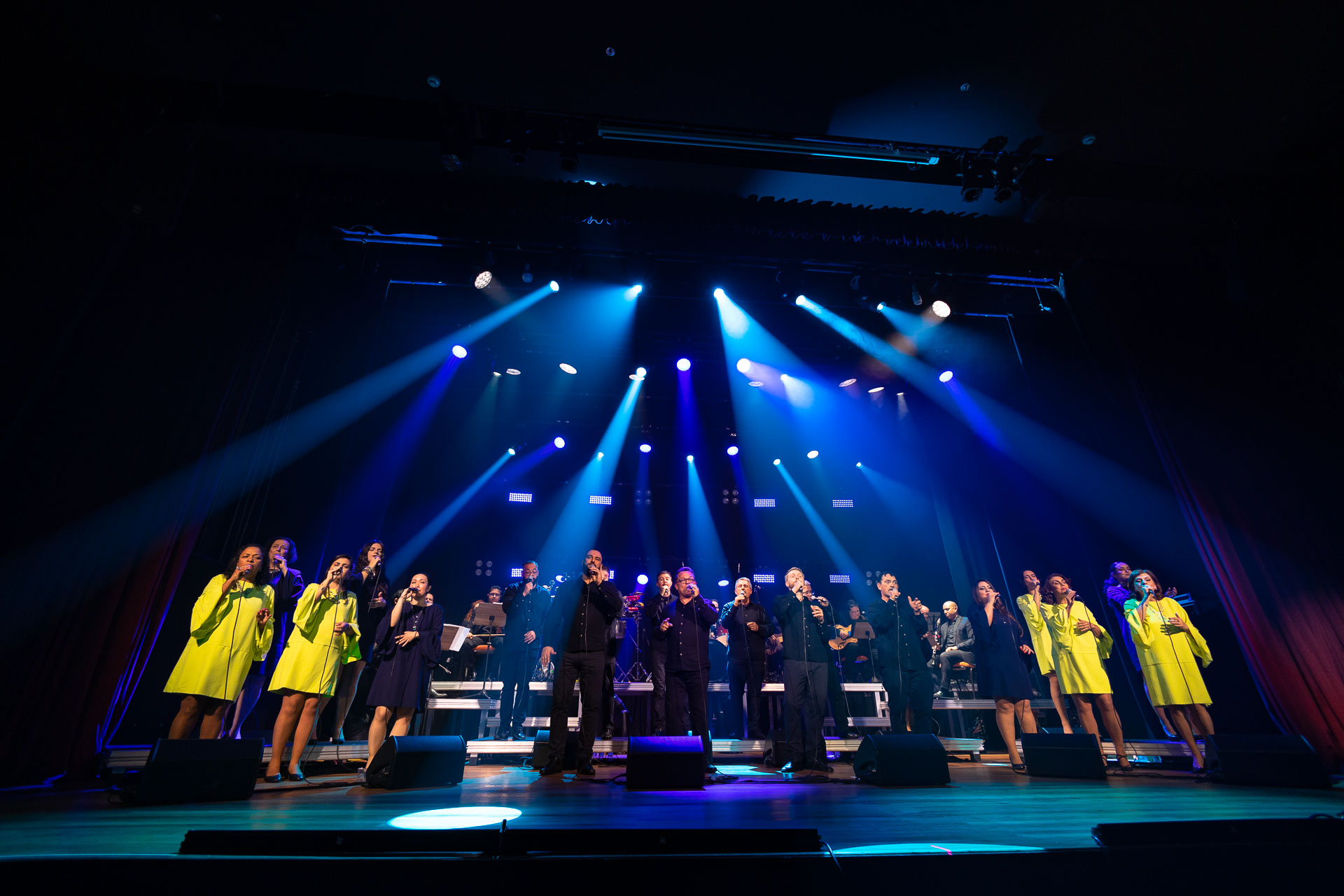 grupo vocal em apresentação musical num palco bastante iluminado