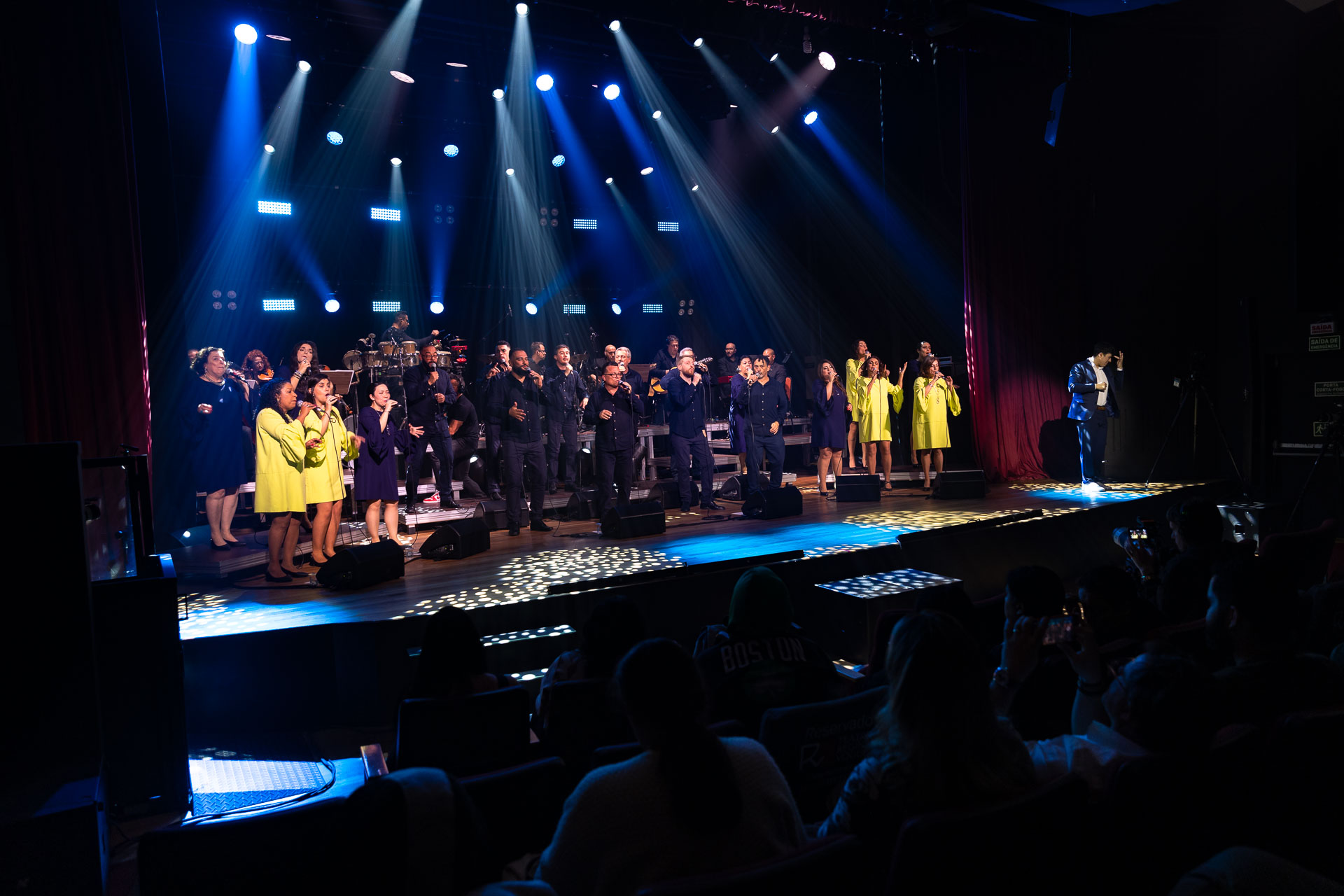 grupo vocal em apresentação musical num palco bastante iluminado