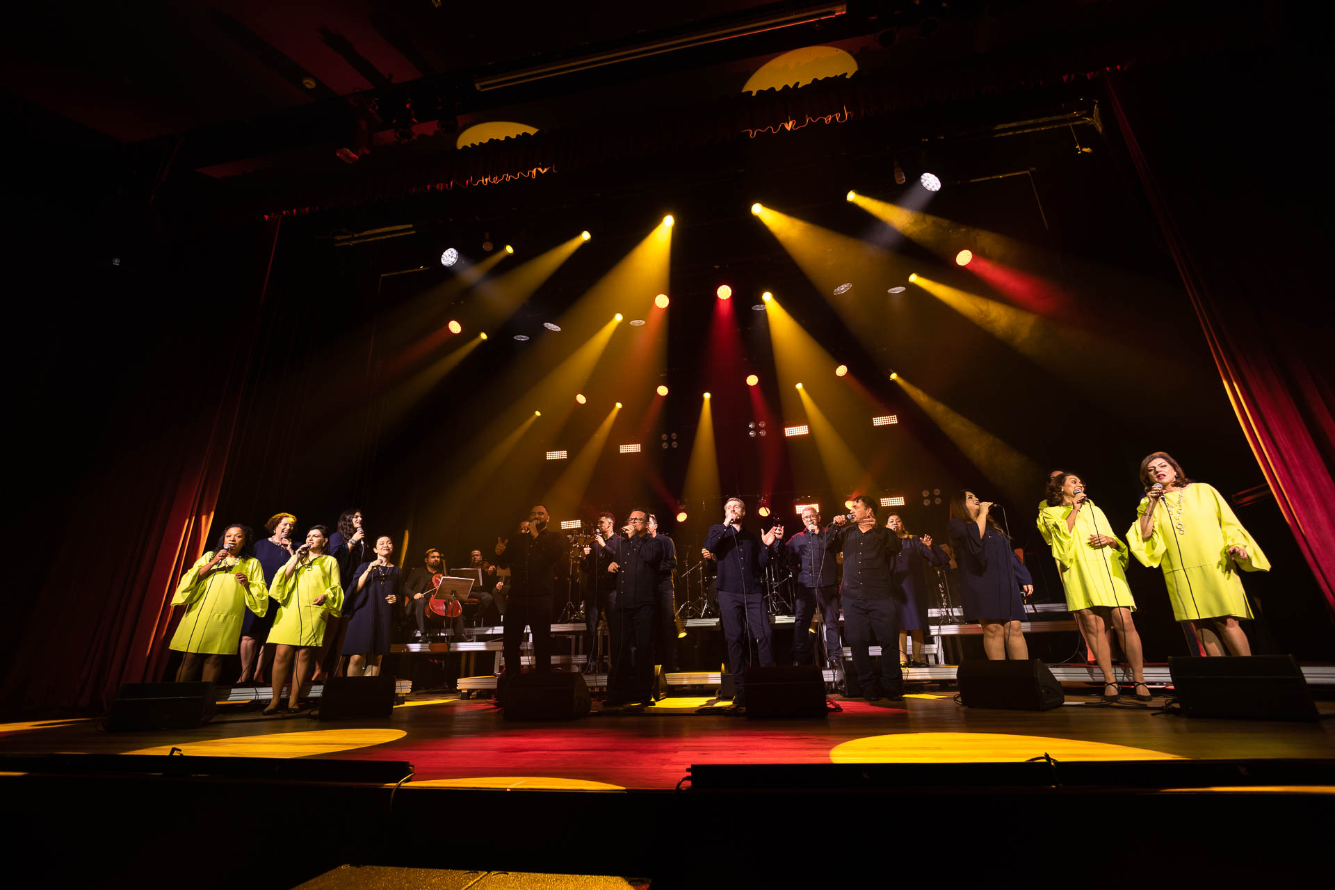 grupo vocal em apresentação musical num palco bastante iluminado