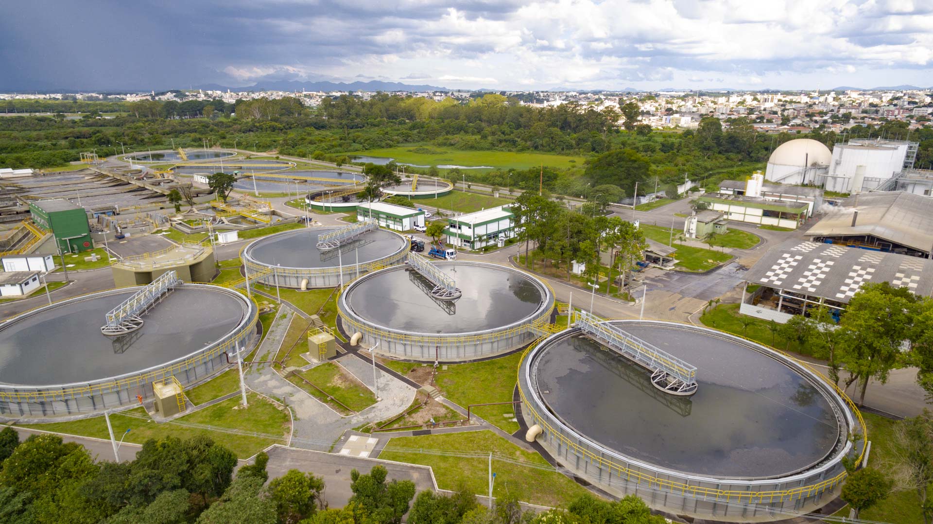 Vista aérea parcial da Estação de Tratamento de Esgoto Belém, destacando grandes tanques circulares de decantação rodeados por passarelas metálicas e áreas gramadas.