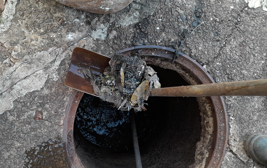 A imagem mostra uma emaranhando cinzento de material retirado da rede de esgoto, em uma pá, sobre a entrada do Ponto de Visitação. 