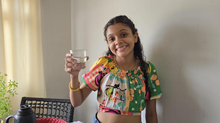 garota sorridente segura copo de água na mão