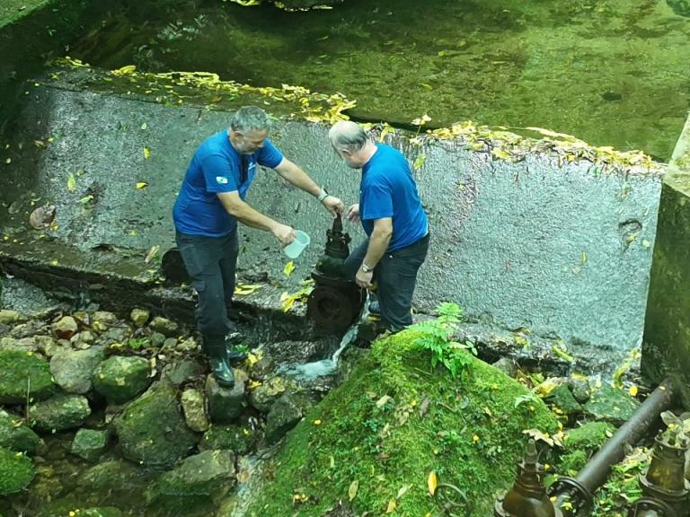 homens coletando amostra de água do rio