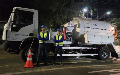 trabalhadores uniformizados e com capacetes possam ao lado do caminhão de hidrojateamento de esgoto