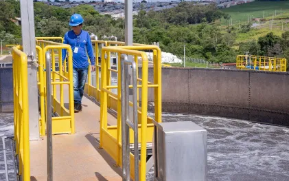 trabalhador caminho em passarela numa estação de tratamento de esgoto