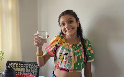 garota sorridente segura copo de água na mão