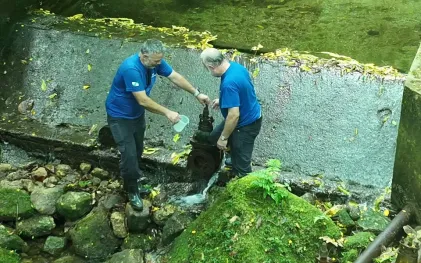 homens coletando amostra de água do rio