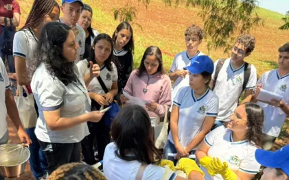 alunos estão num espaço aberto proximo ao rio e estão analisando a qualidade da agua com kit 