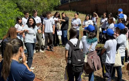 alunos estão num espaço aberto proximo ao rio discutindo em circulo sobre a bacia hidrográfica