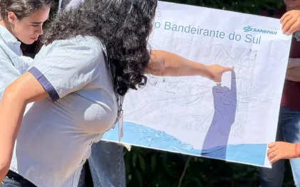 alunos estão num espaço aberto proximo ao rio discutindo em circulo sobre a bacia hidrográfica