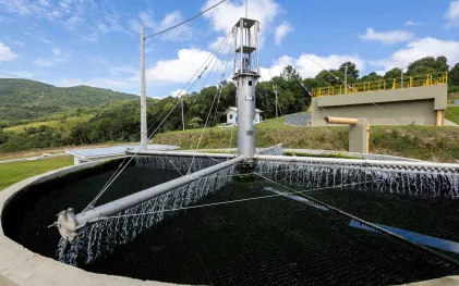 Filtro biológico circular em operação na Estação de Tratamento de Esgoto de Rio Branco do Sul, com braço mecânico distribuindo água sobre a base de filtragem