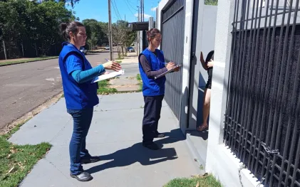 técnicos com uniformes da cor azul abordam clientes no portão de suas casas