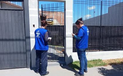 técnicos com uniformes da cor azul abordam clientes no portão de suas casas