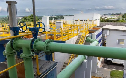 Vista superior de tanques abertos de concreto de uma estação de tratamento de água, mostrando as etapas de movimentação e purificação da água sob a luz do dia.