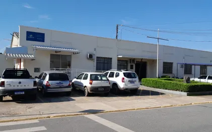 Fachada da Central de Relacionamento da Sanepar em Quitandinha, um prédio térreo branco com placa azul de identificação e veículos estacionados na frente.