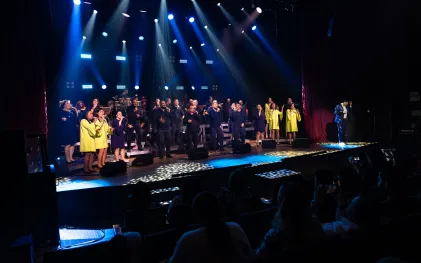 grupo vocal em apresentação musical num palco bastante iluminado