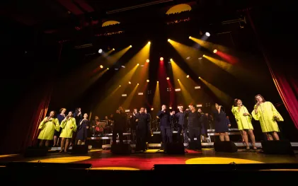 grupo vocal em apresentação musical num palco bastante iluminado