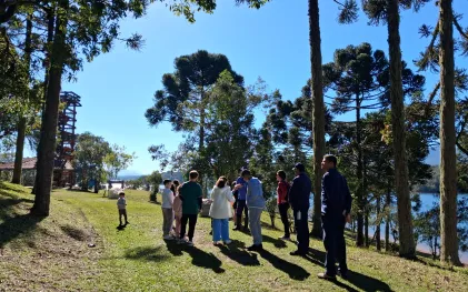 Crianças passeiam em ambiente aberto e ensolarado, na natureza.