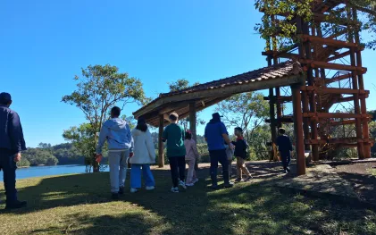 Crianças passeiam em ambiente aberto e ensolarado, na natureza.