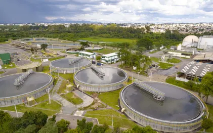 Vista aérea parcial da Estação de Tratamento de Esgoto Belém, destacando grandes tanques circulares de decantação rodeados por passarelas metálicas e áreas gramadas.