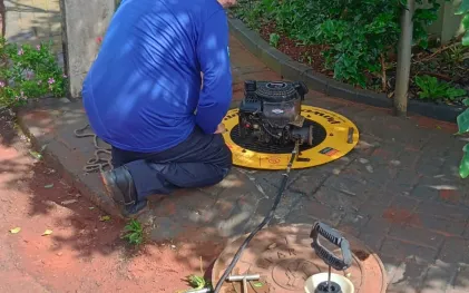 empregado manuseando máquina que faz o teste de fumaça na rede de esgoto