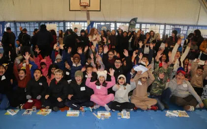Crianças alinhadas com as mãos para o alto durante um evento da Sanepar.